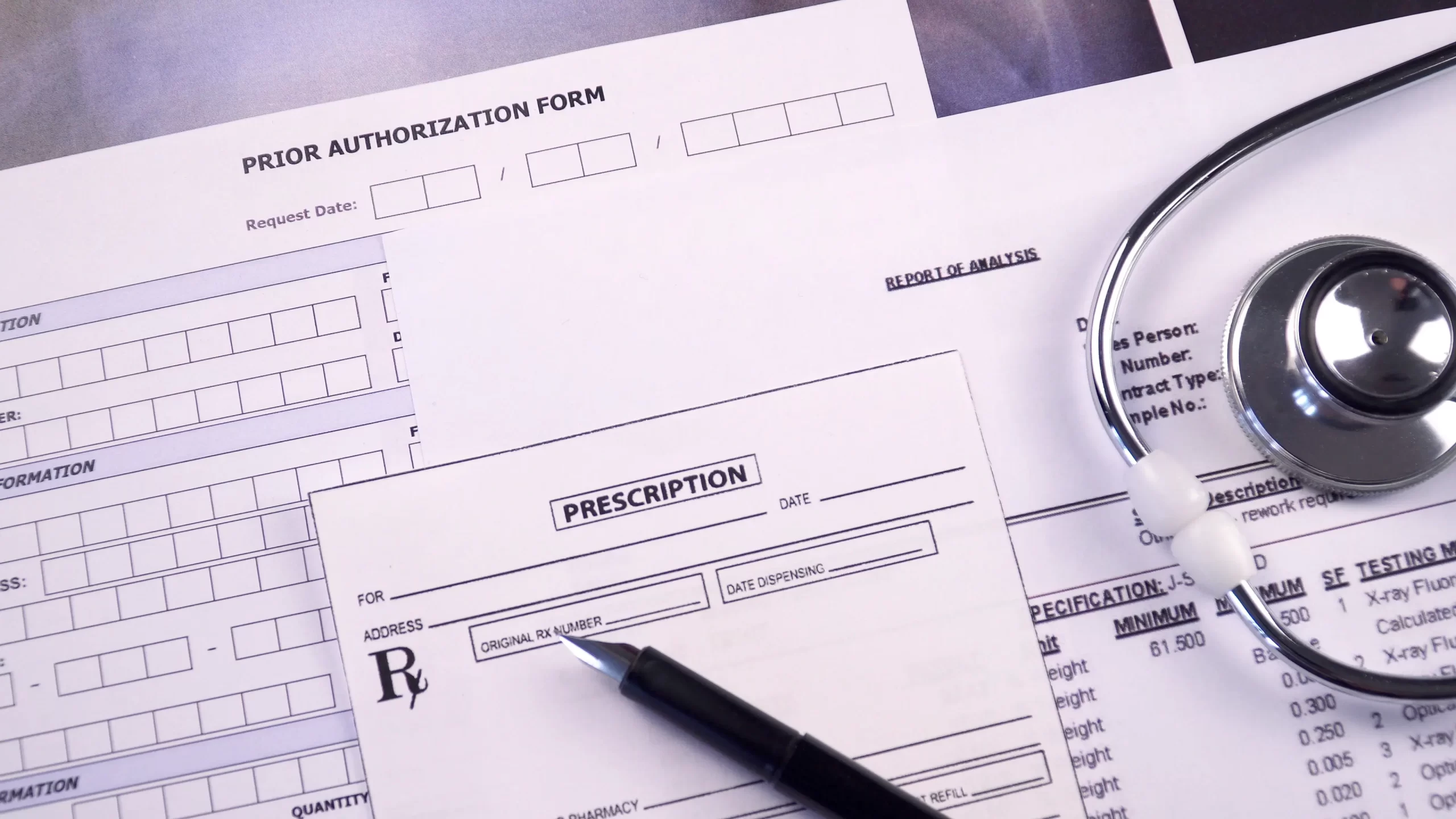 Prior authorization form, report of analysis form, x-ray picture and prescription blank next to the stethoscope and pen