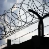 Dramatic clouds behind barbed wire fence on a prison wall