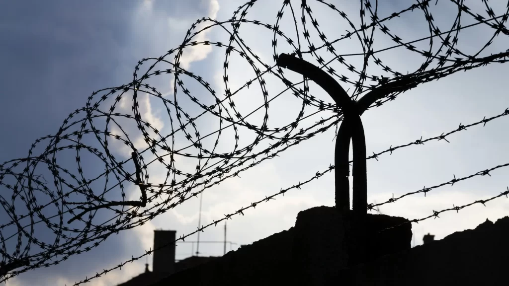 Dramatic clouds behind barbed wire fence on a prison wall