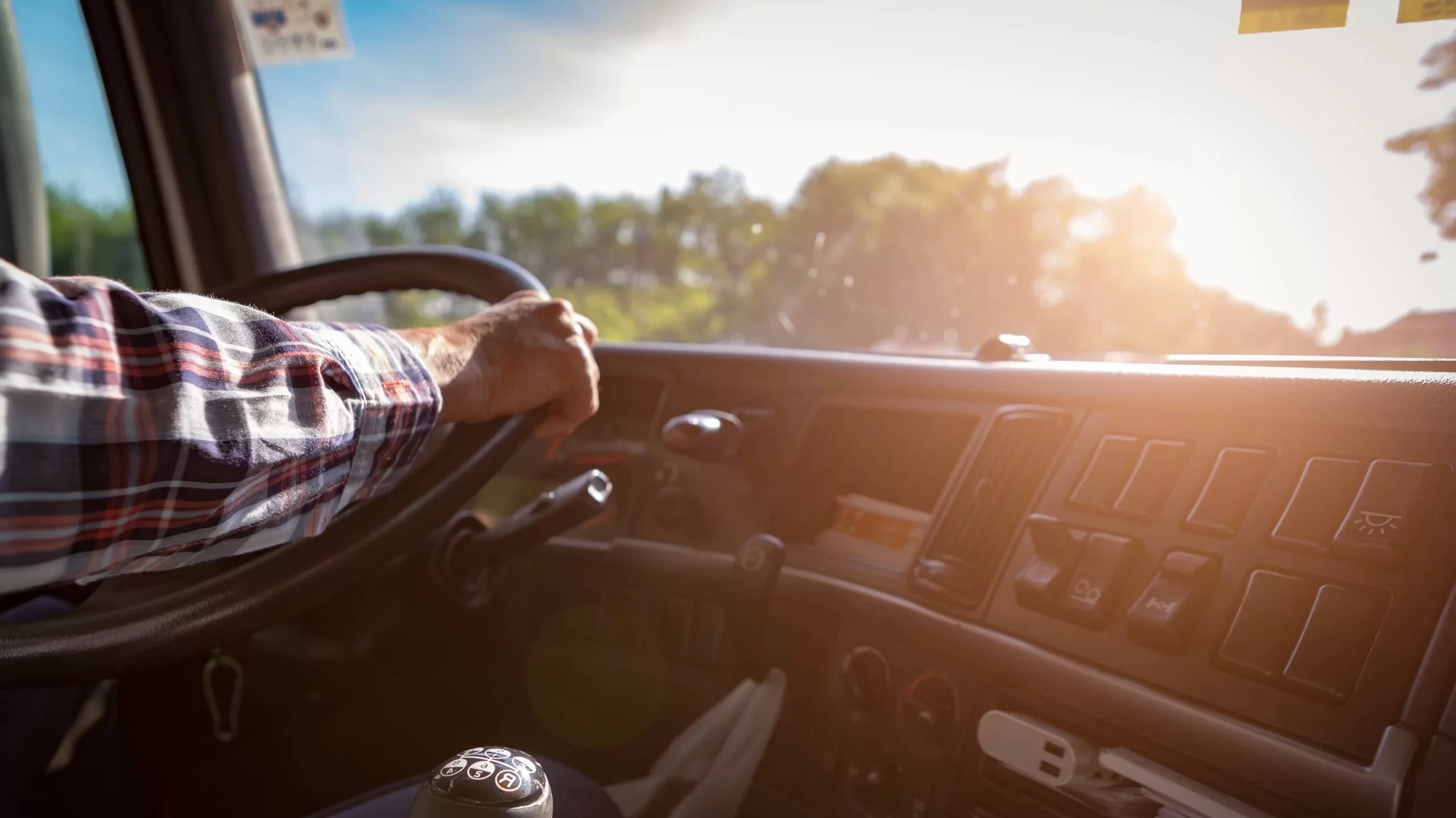 Truck driver keeps driving with one hands and change gears,The man Behind Semi Truck Steering Wheel,spot focus.