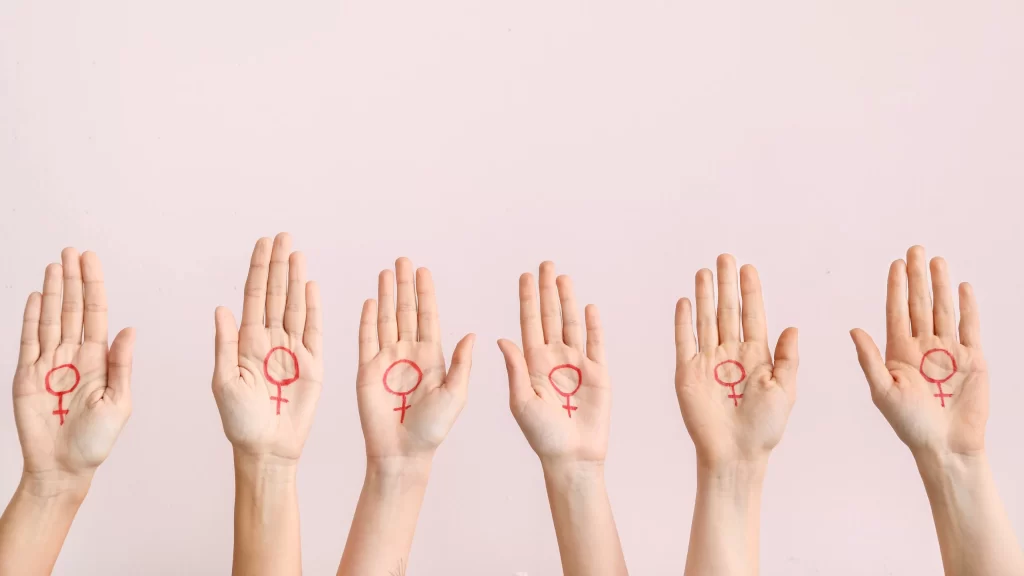 Women with drawn symbols of woman on their palms against color background. Concept of feminism