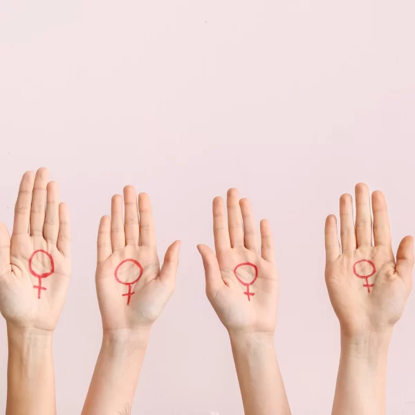 Women with drawn symbols of woman on their palms against color background. Concept of feminism