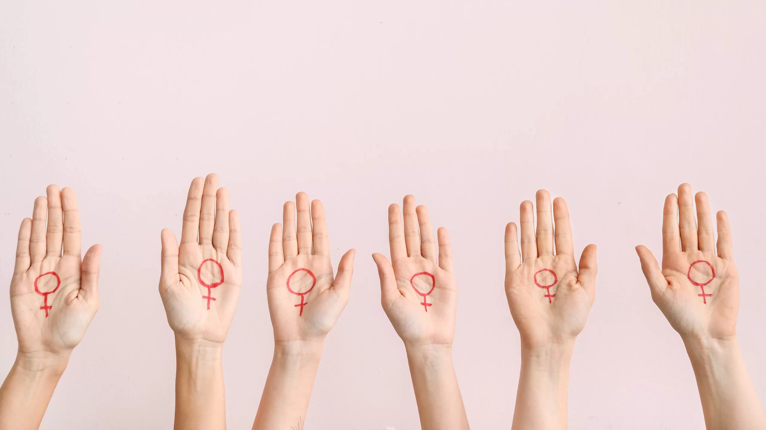 Women with drawn symbols of woman on their palms against color background. Concept of feminism