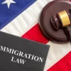 Immigration law text on black book and judge gavel on US of America flag background, top view. Migration, emigration visa in USA concept