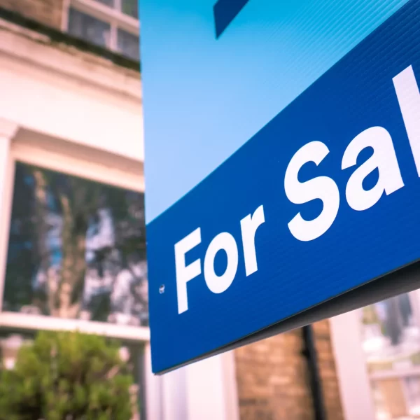 Estate agent 'For Sale' sign on street of houses