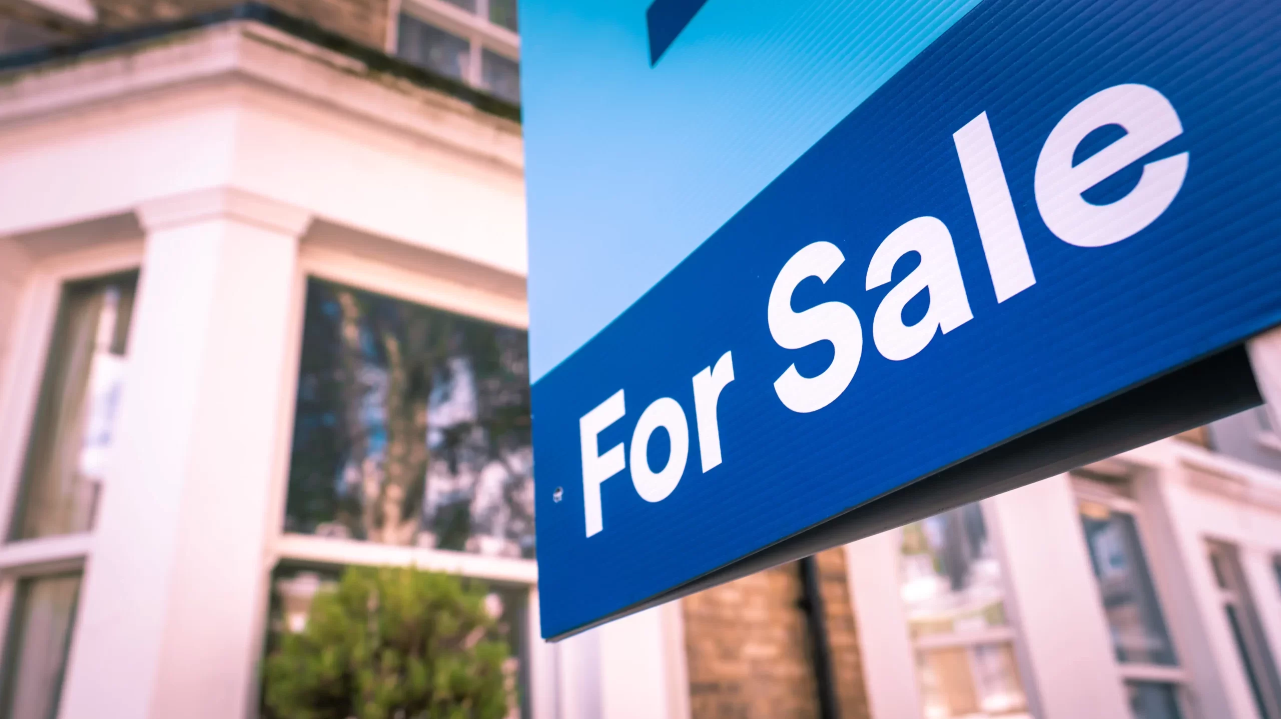 Estate agent 'For Sale' sign on street of houses