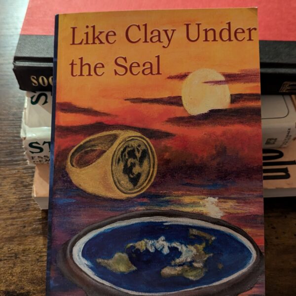 A photo of “Like Clay Under the Sun” resting against a pile of other books.